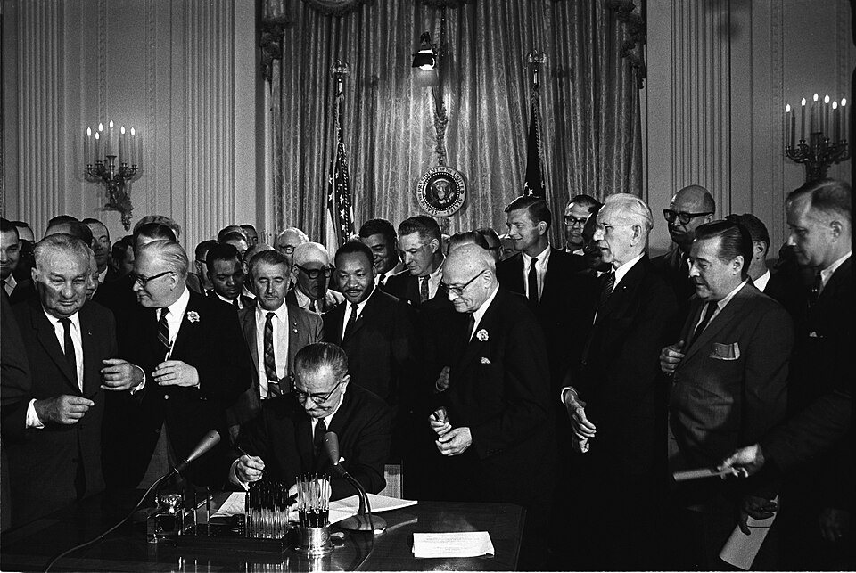 President Johnson signing the Civil Rights Act as leaders look on